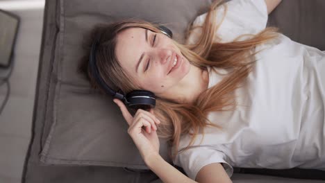 Chica-Con-Auriculares-Disfrutando-Del-Ritmo-De-La-Música-En-Un-Sofá