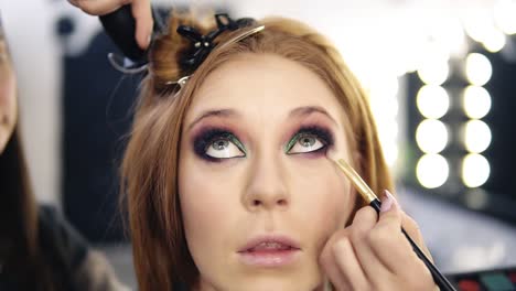 Front-Footage-Of-A-Blonde-Beautiful-Model-Sitting-And-Looking-Up-While-Make-Up-Artist-Finishing-Her-Smoky-Eyes