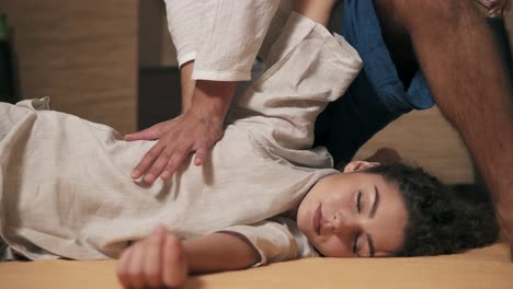 Male-Thai-Massagist-Is-Stretching-Woman's-Hand-And-Side