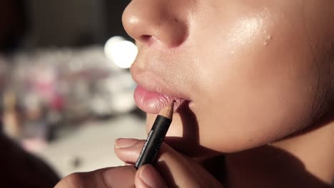 Cropped-View-Of-Makeup-Artist-Applying-Beige-Lip-Pencil-On-Model-Lips