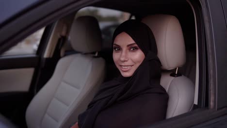 Beautiful-Young-Muslim-Womanin-Black-Traditional-Hijab-On-A-Head-Sitting-In-The-Car,-On-The-Driver-Seat