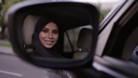 Car-Mirror-Reflection-Shot-Of-A-Happy-Young-Muslim-Woman-In-Black-Hijab-With-Professional-Makeup