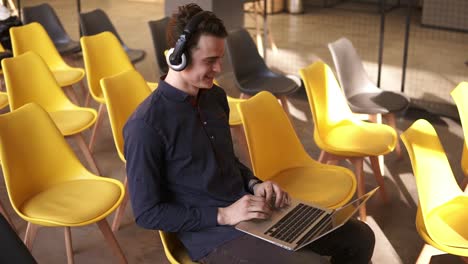 Young-Attractive-Guy-Is-Dancing-To-Music-In-His-Headphones-While-Working-On-Laptop