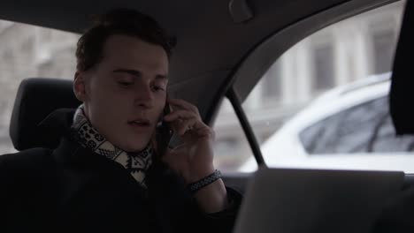 Attractive-Young-Guy-Talking-To-Someone-On-The-Phone-While-Riding-In-A-Car