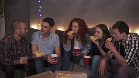 Young-People-Cheerful-Men-And-Women-Are-Eating-Cheesy-Pizza,-Chatting-Relaxing-During-Indoor-Party-In-Apartment-In-A-Loft-Room