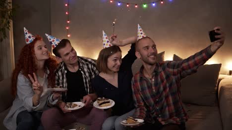Cheerful,-Young-Friends-Or-Two-Couples-Having-Small,-Cozy-Birthday-Celebration,-Sitting-Together-In-Festive-Cones-On-The-Couch-And-Taking-Selfie-Using-A-Mobile-Phone-1