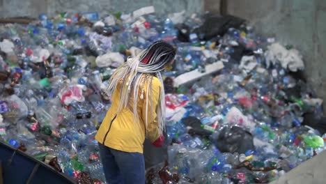 Stylish-Woman-In-Yellow-Jacket,-Protective-Glasses-And-Gloves-Sorting-Plastic-Bottles-From-Black-Bags