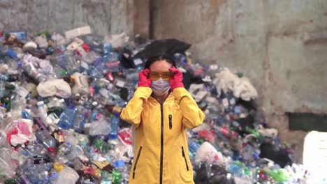 Portrait-Of-Young-Woman-Worker-In-Red-Rubber-Gloves-Putting-On-A-Mask-And-Protective-Eyeglasses,-Preparing-For-Working-Day-Recycling-Factory