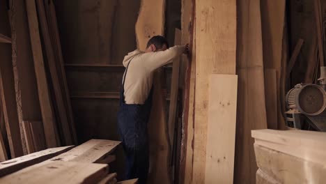 A-Worker-In-A-Carpentry-Workshop-Full-Of-Timber-Chooses-The-Suitable-Material-For-Work