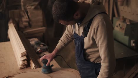 The-Joiner-Finishes-Grinding-The-Piece-Of-Wood,-Turns-Off-The-Grinder-And-Checks-The-Surface-For-Roughness