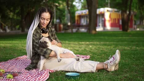 Girl-With-Dreadlocks-Sitting-On-Plaid-On-Lawn-In-A-Park