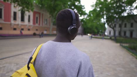 Rare-View-Of-Young-Tourist-Listening-To-Music-Using-Headphones-And-Smart-Phone-Walk-In-Beautiful,-Old-City