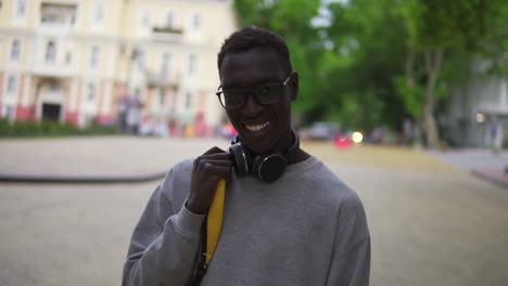 Portrait-Of-Young-Man-In-Stylish-Glasses-And-Headphones-Looking-At-Camera-Smile-Feel-Happy
