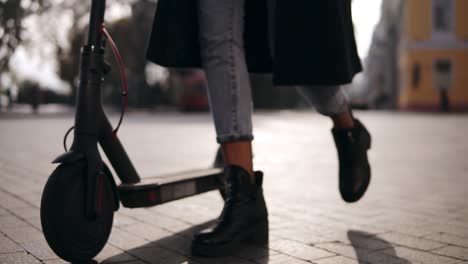 Close-Up-Of-Legs-Of-A-Young-Woman-Scooter-Driver-Walking-With-Her-Ecological-Transport,-Electric-Scooter