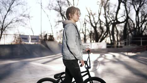 A-Young-Boy-With-Short-Dreadlocks-In-The-Skate-Park-Wak-Lking-By-His-Bmx-Bike