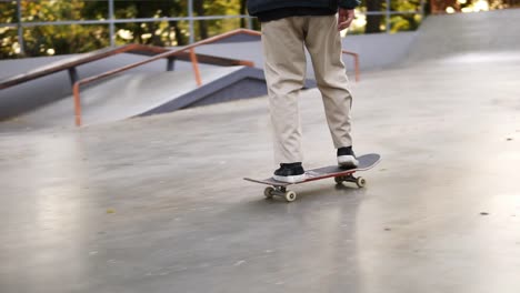 Closeup-View-Of-Man's-Legs-In-Black-Sneakers-And-Beige-Pants-Skateboarding,-Exersicing-In-Skate-Park