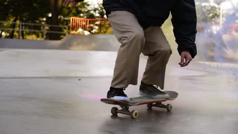 Skater-Irreconocible-Saltando-Y-Haciendo-Flip-360-Con-Su-Tablero-Y-Salpicando-La-Arena-Colorida-De-Su-Tablero