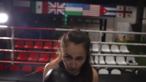 Female-Boxer-Punching-Camera,-Shadow-Boxing-During-Workout-In-Dark-Gym