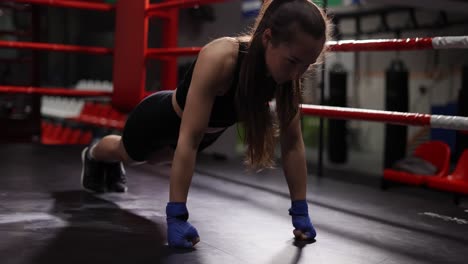 Brunette-Woman-Doing-Push-Ups-On-Fists-While-Training-In-Boxing-Ring