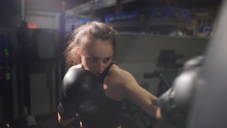 Female-Boxer-Punching-Boxing-Bag-During-Training-In-Gloves