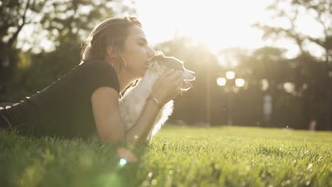 Side-View-Footage-Of-A-Young-Woman-In-Black-T-Shirt-Lying-On-The-Grass-With-Her-Little-Dog-And-Looking-Straight-Together-Thoughtfully