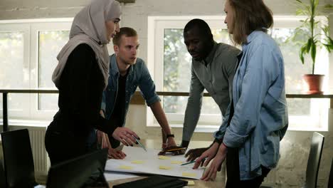 Multikulturelle-Gruppe-Von-Menschen-Muslimische-Frau,-Mann-Und-Mann-Und-Frau-Diskutieren-Gemeinsam-Ein-Projekt-Im-Büro-Und-Lehnen-Sich-An-Den-Tisch