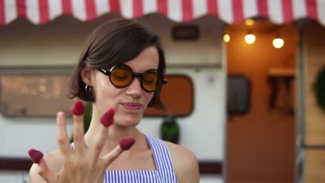 Stylish-Woman-With-Short-Hair-And-Sunglasses-Eats-Raspberry-From-Fingers