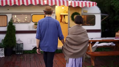 Romantic-Couple-Living-Or-Having-Vacation-In-Trailer-Girl-Covered-With-Brown-Plaid-Walking-With-Her-Man-Inside-To-The-Trailer,-Holding-Hands