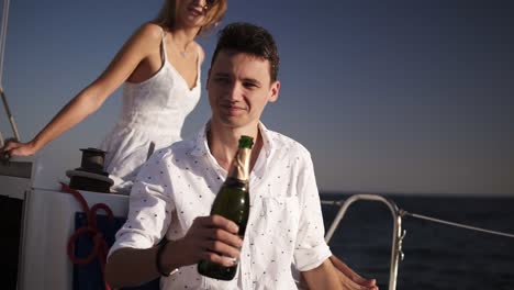 Two-People-On-Resort,-Happy-Couple-Drinking-Champagne-On-Yacht,-Rest-At-Water,-Romantic-Couple-Drink-Beverage-To-Sea,-Glasses-In-Hands-Male-Offering-And-Female-On-The-Background