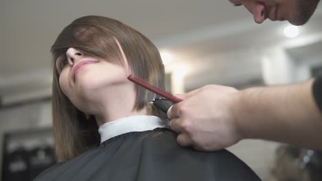 Closeup-View-Of-A-Hairdresser's-Hands-Cutting-Hair-With-Scissors