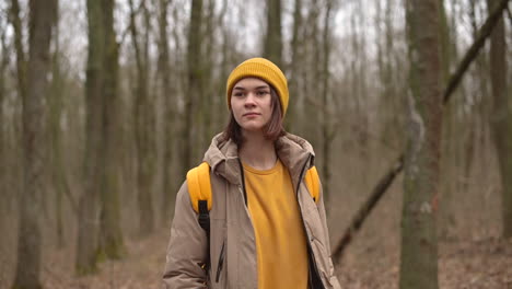 A-Young-Girl-In-A-Yellow-Woolen-Hat-Walks-Through-The-Forest-Looking-From-Side-To-Side