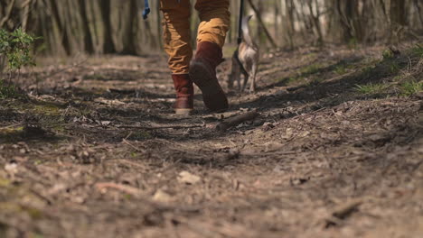 The-Boots-Of-An-Unrecognizable-Person-Walking-Through-The-Forest-With-A-Dog