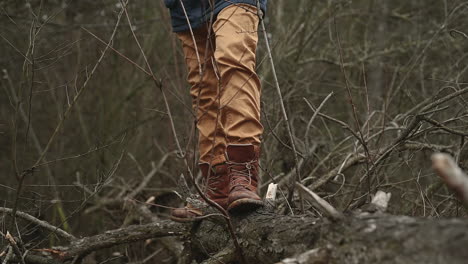 The-Boots-Of-An-Unrecognizable-Person-Stand-On-A-Fallen-Tree