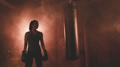 Female-Boxer-Rests-Next-To-The-Punching-Bag