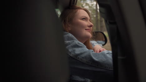 Red-Haired-Woman-Enjoys-A-Drive-Through-The-Countryside-From-The-Window-Of-The-Car