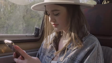 A-Beautiful-Young-Woman-Typing-On-Her-Cell-Phone-While-Smiling-During-A-Roadtrip-In-The-Caravan