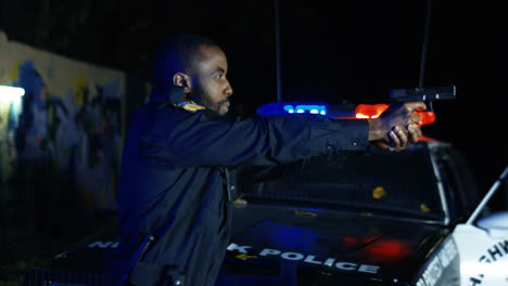 Side-View-On-Young-Cop-Pointing-Gun-At-Somebody-Outdoors-At-Night