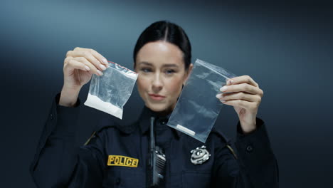 Young-Attractive-Policewoman-Holding-Two-Plastic-Bags-With-Crime-Proves-In-Hands-With-White-Powder-Like-Cocaine-And-Cigarette-Butts-Examining-Them