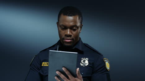 Gut-Aussehender-Polizist,-Der-Auf-Dem-Tablet-Gerät-Tippt-Und-Scrollt,-Während-Er-Informationen-Durchsucht-Und-Sucht