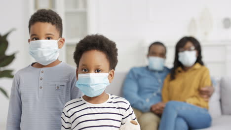 Portrait-Of-Small-Kids-In-Medical-Masks-Looking-At-Camera-At-Home