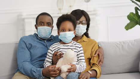Young-Family-With-Cute-Little-Kid-In-Medical-Masks-At-Home-On-Lockdown