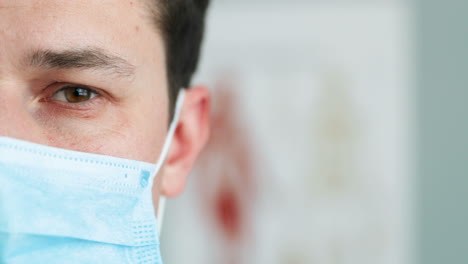 Close-Up-Of-Half-Face-Of-Young-Sad-Man-Physician-In-Blue-Medical-Mask-Looking-At-Camera