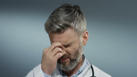 Close-Up-Of-The-Tired-Male-Doctor-With-Gray-Hair-Putting-Stethoscope-On-His-Neck-And-Taking-Off-Glasses-After-Hard-Working-Day