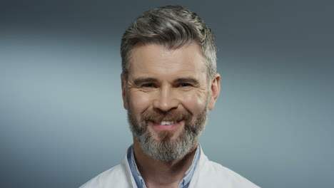 Portrait-Shot-Of-The-Good-Looking-Grey-Haired-Man-Doctor-With-A-Beard-Smiling-Cheerfully-To-The-Camera