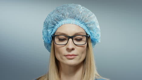 Close-Up-Of-The-Young-Blond-Good-Looking-Woman-Doctor-With-Serious-Face-In-Blue-Hat-And-Glasses-Looking-At-The-Camera