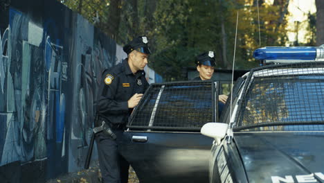 Polizist-Und-Polizistin-Verhaften-Jungen-Männlichen-Täter-Und-Sitzen-Ihn-Im-Polizeiauto