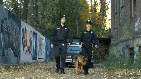 Polizist-Und-Polizistin-In-Uniformen,-Die-Mit-Schäferhund-Spazieren-Gehen