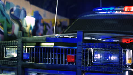 Close-Up-Of-The-Bumper-Of-Police-Car-With-Number-Table-Police-Word-In-Dark-Night-Outdoors