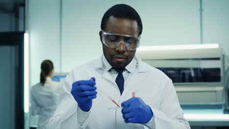 Young-Man-Laboratory-Scientist-Making-A-Blood-Test-With-A-Tube-In-Hands