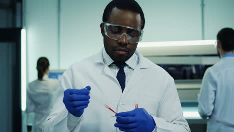 Portrait-Of-The-Handsome-Male-Laboratory-Worker-Making-A-Blood-Test-In-The-Glass-Tube-In-Hands